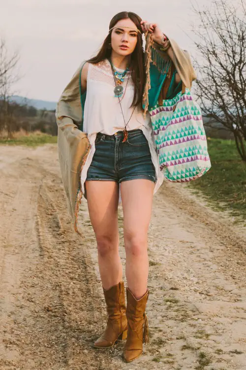 A woman wears cowboy boots with shorts and a boho shirt
