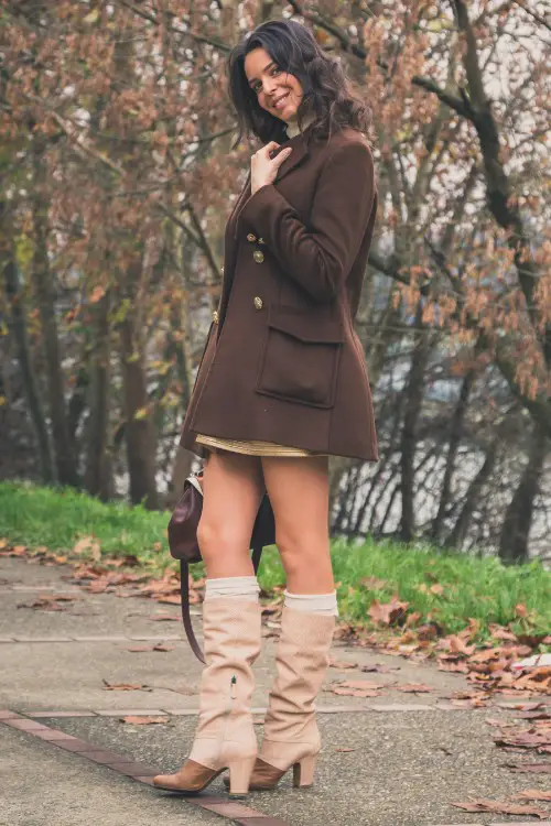 A woman wears cowboy boots with trench coat