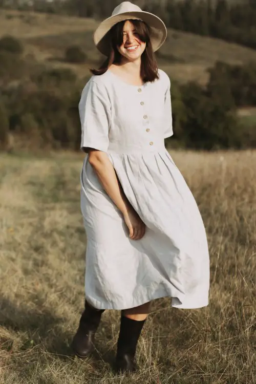 A woman wears cowboy boots with white shirt dress