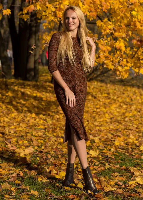 A woman wears fitted brown dress with ankle cowboy boots