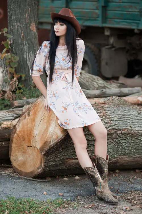 A woman wears floral cowboy boots with a pair of cowboy boots