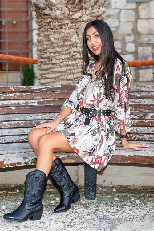 A woman wears floral dress with black cowboy boots