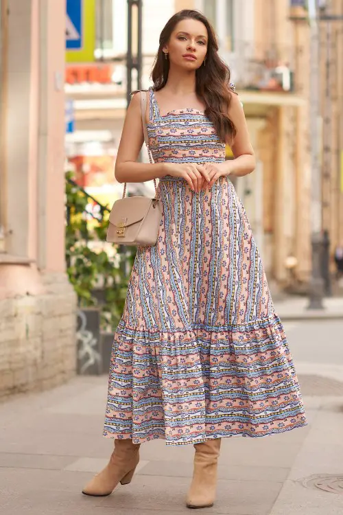 A woman wears flowy dress with cowboy boots