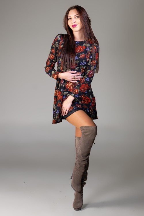 A woman wears knee high cowboy boots with a floral dress