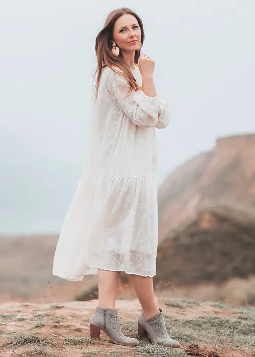 A woman wears lace dress with ankle cowboy boots