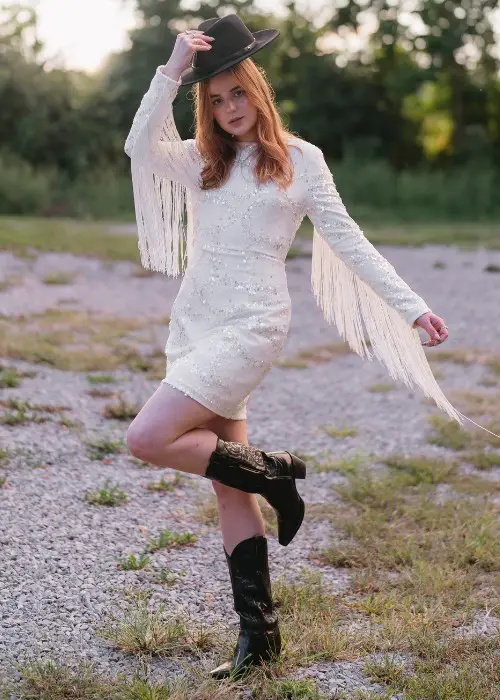 A woman wears lace dress with black cowboy boots