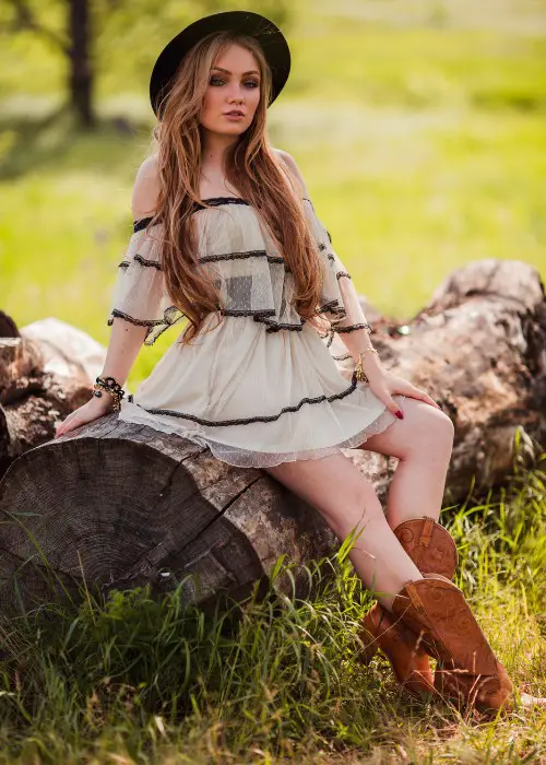 A woman wears lace dress with brown cowboy boots