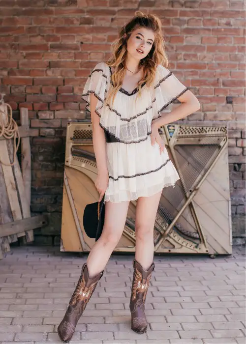 A woman wears mini lace dress with brown cowboy boots