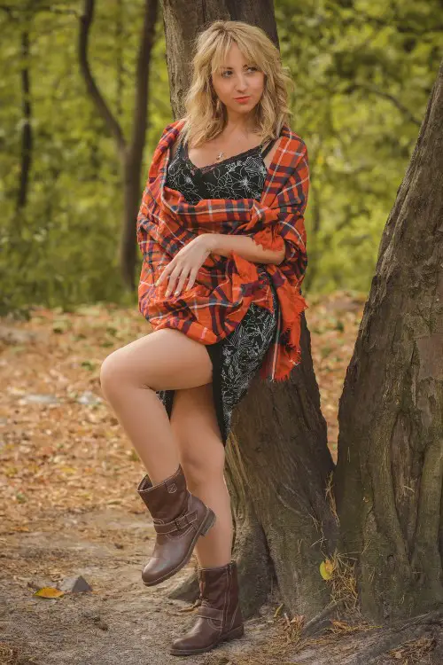 A woman wears plaid coat with dress and short cowboy boots
