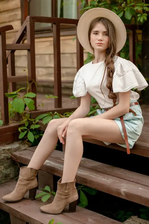A woman wears shorts with ankle cowboy boots