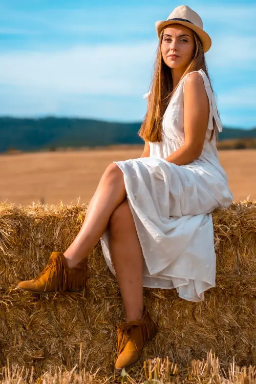 A woman wears suede booties with white dress