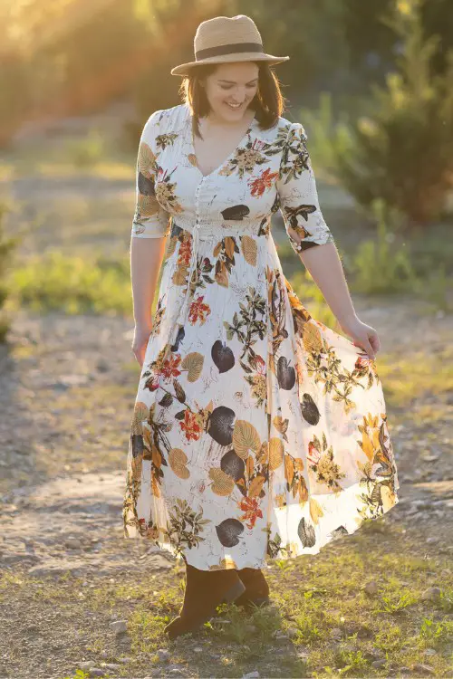 A woman wears suede cowboy boots with floral midi dress