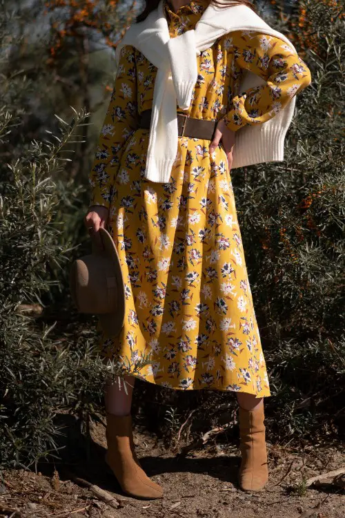A woman wears suede cowboy boots with yellow boho dress