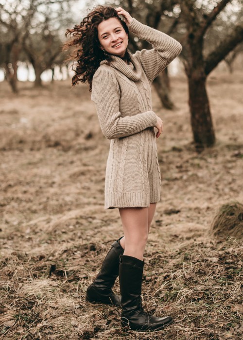 A woman wears sweater dress with black cowboy boots
