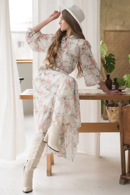 A woman wears white cowboy boots with floral dress