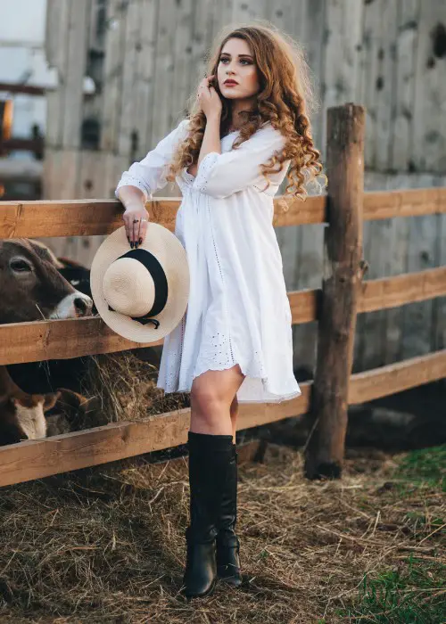 A woman wears white dress with black cowboy boots