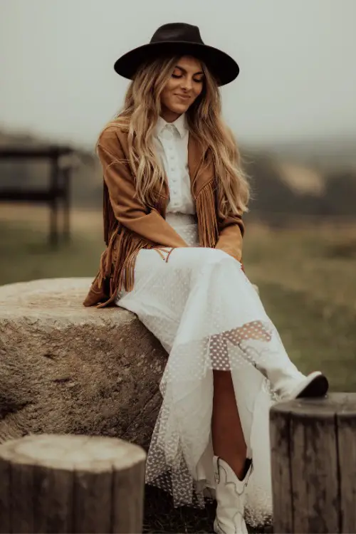 A woman wears white dress with suede coat and a white dress