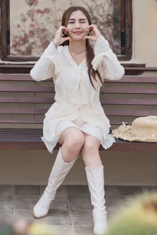 A woman wears cream cowboy boots with a dress.