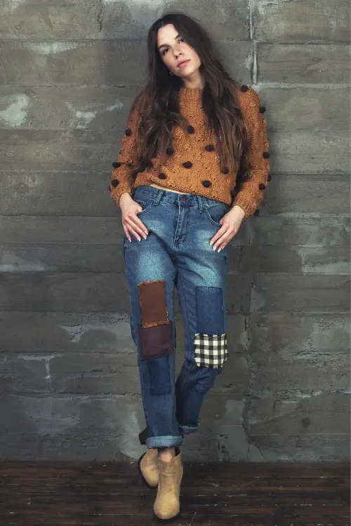 A woman wears brown cowboy boots with jeans and a sweater