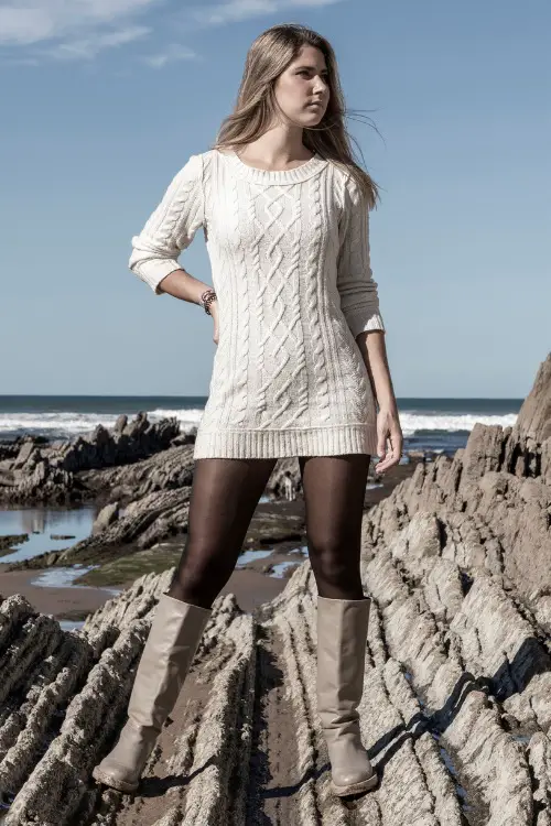 A woman wears grey cowboy boots with a sweater dress