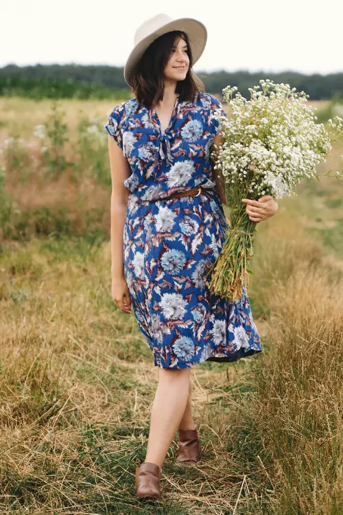 A woman wears cowboy boots with a floral dress