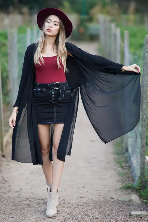 A woman wears ankle cowboy boots with a short skirt, red toe and light coat