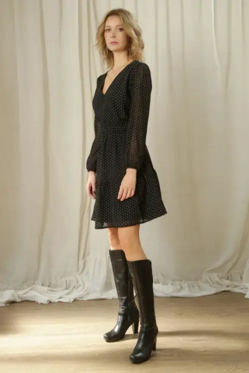 A woman wears a black dress with black cowboy boots