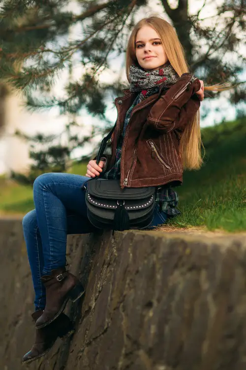 A woman wears cowboy boots with jeans and a leather coat