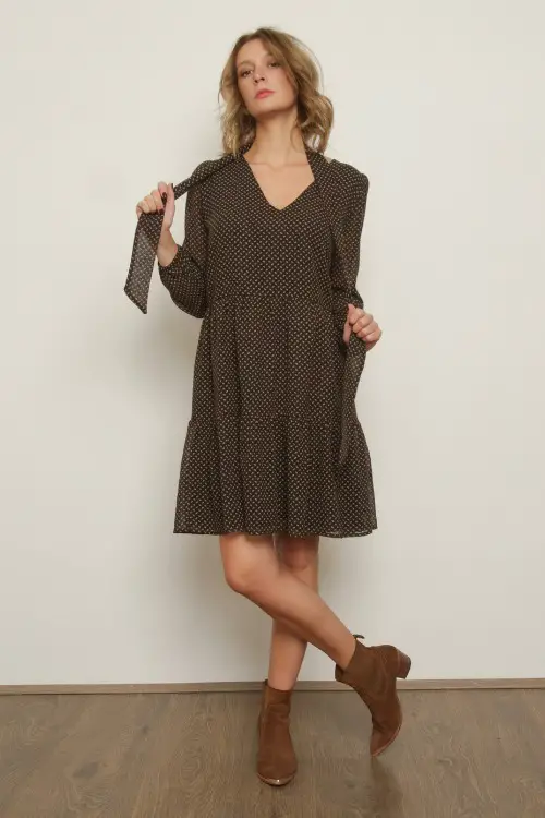 A woman wears a dotted dress with brown cowboy boots