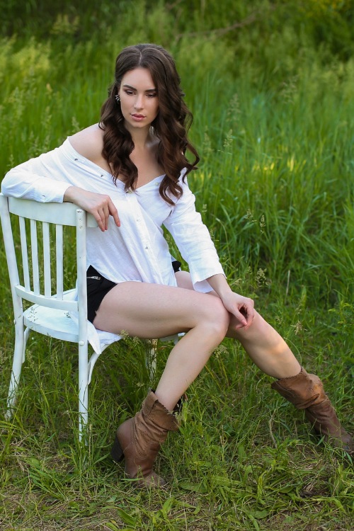 A woman wears brown cowboy boots with a white top and shorts