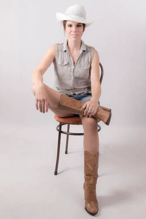 A woman wears brown cowboy boots with shorts and a sleeveless top