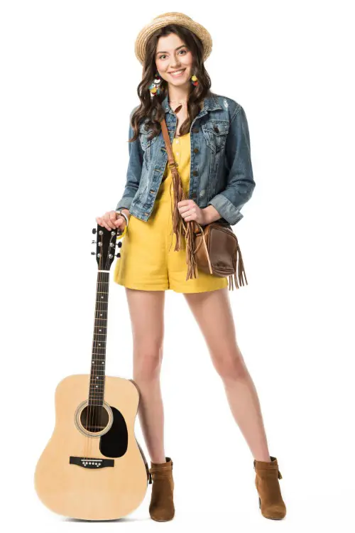 A woman wears brown cowboy boots with a denim shirt and a yellow romper