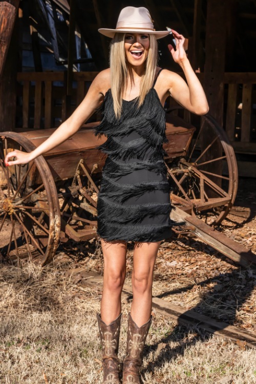 A woman wears cowboy boots with a black tiered dress