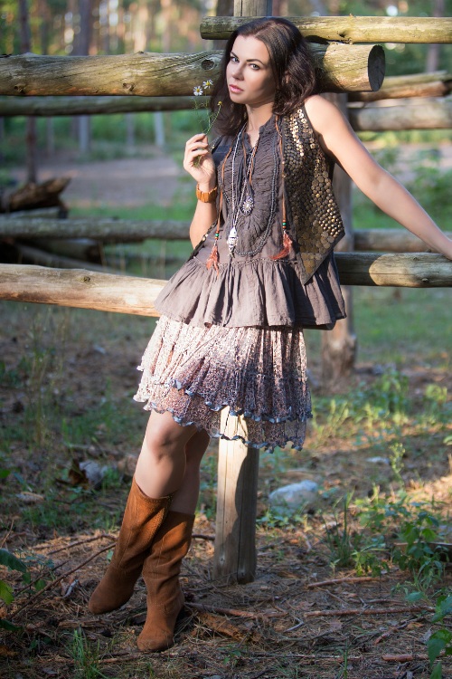 A woman wears cowboy boots with a flowy dress