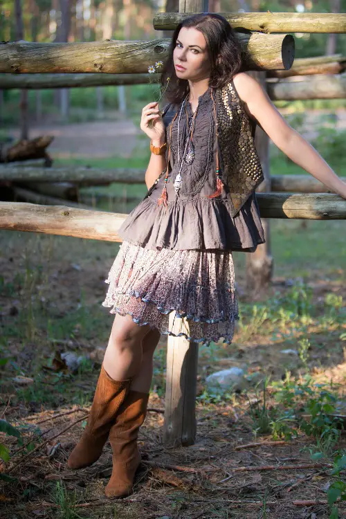 A woman wears cowboy boots with a flowy dress