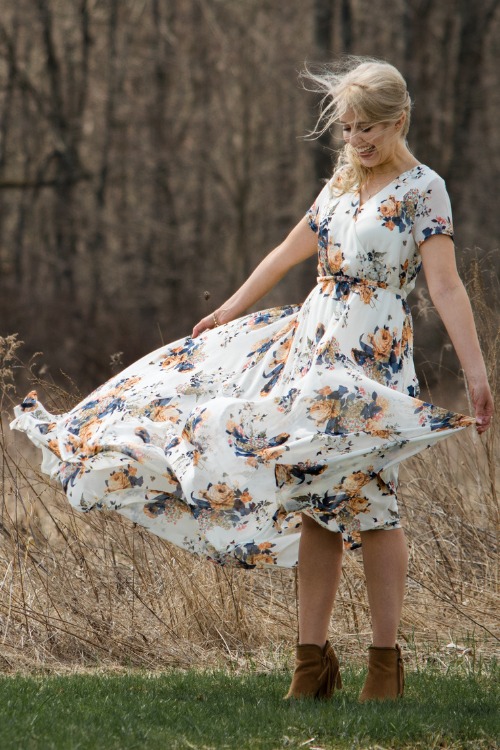 a woman wears cowboy boots with a flowy floral dress