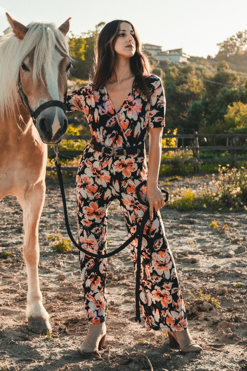 A woman wears cowboy boots with a jumpsuit