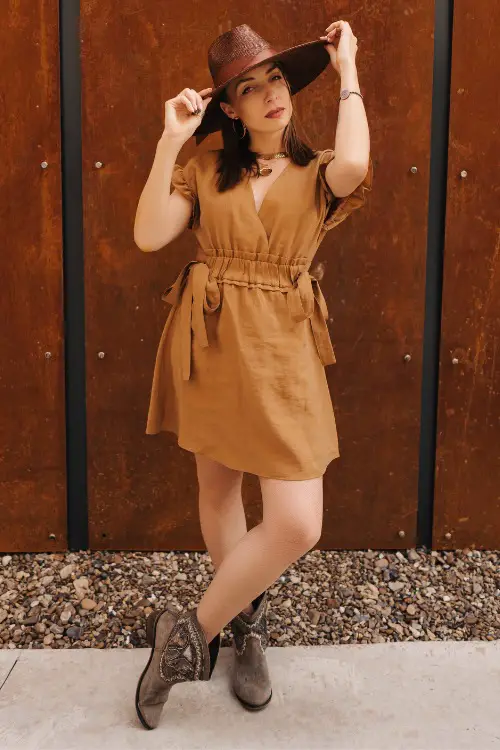 A woman wears cowboy boots with a khaki dress