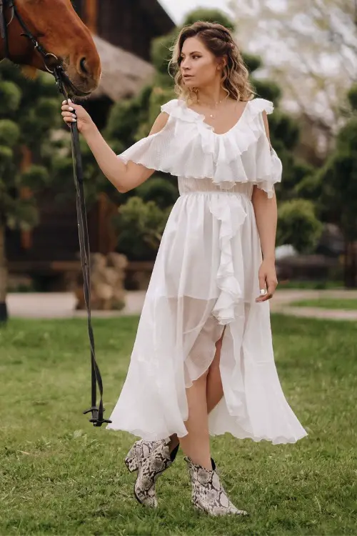 A woman wears cowboy boots with a lace dress