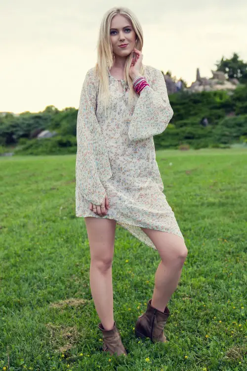 A woman wears cowboy boots with a light floral dress