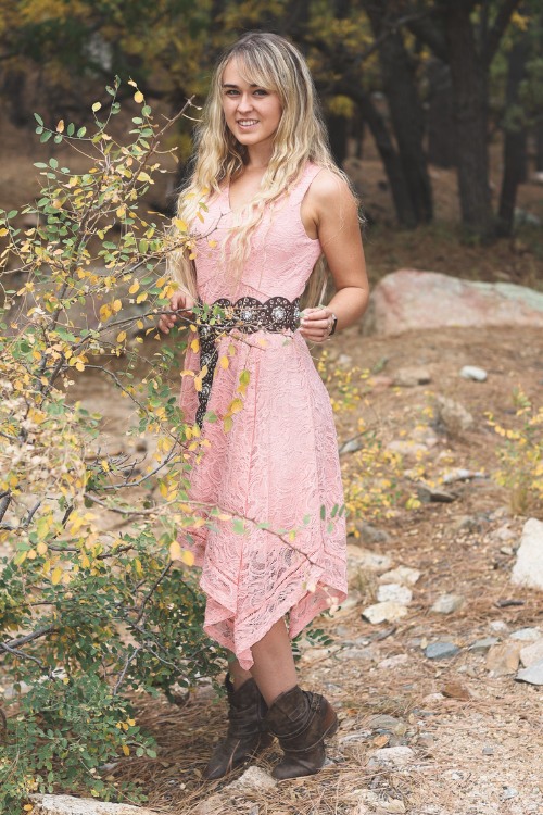 A woman wears cowboy boots with a pink dress
