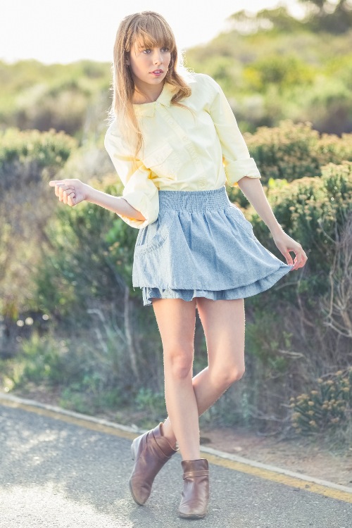 a woman wears cowboy boots with a skirt and a yellow blouse