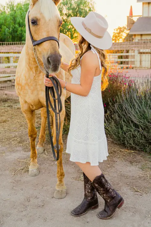 a woman wears cowboy boots with a white lace dress