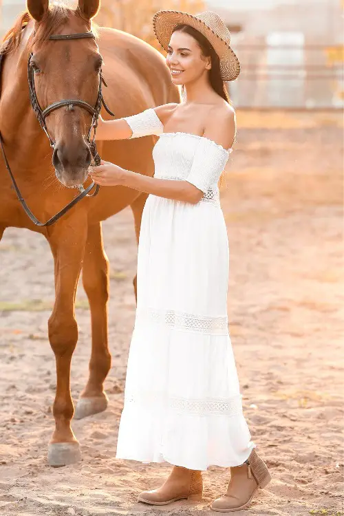 A woman wears cowboy boots with an off-shoulder dress