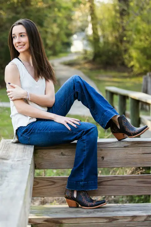 a woman wears cowboy boots with flare jeans and a white v neck top