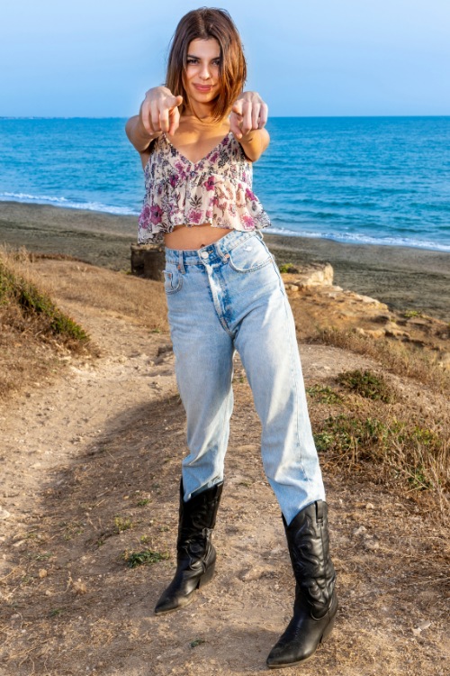 a woman wears cowboy boots with jeans and a mini floral top