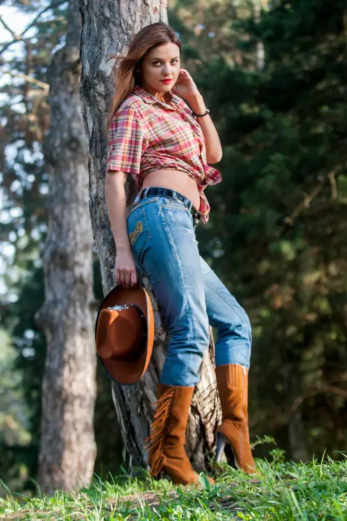 a woman wears cowboy boots with jeans and a plaid shirt