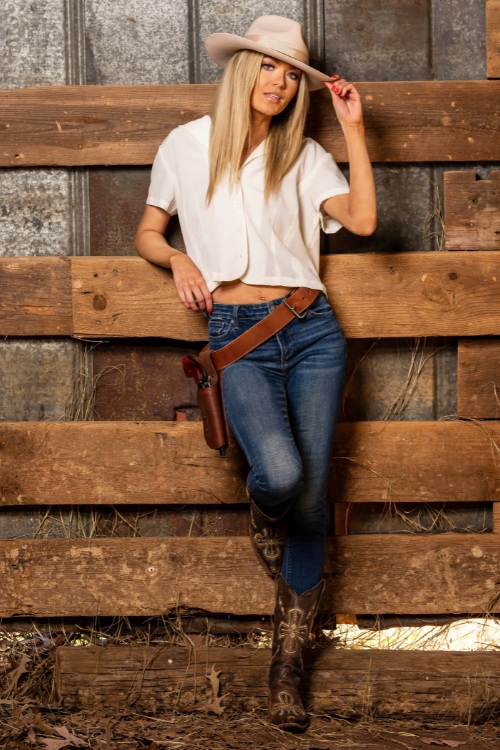 A woman wears cowboy boots with a skinny jeans and a shirt