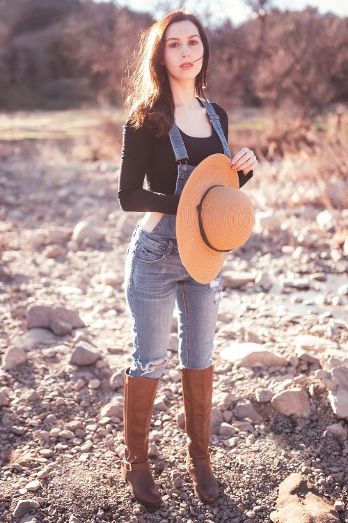 A woman wears cowboy boots with jeans, black top