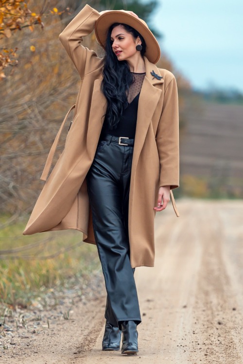 A woman wears cowboy boots with leggings, long coat and black top